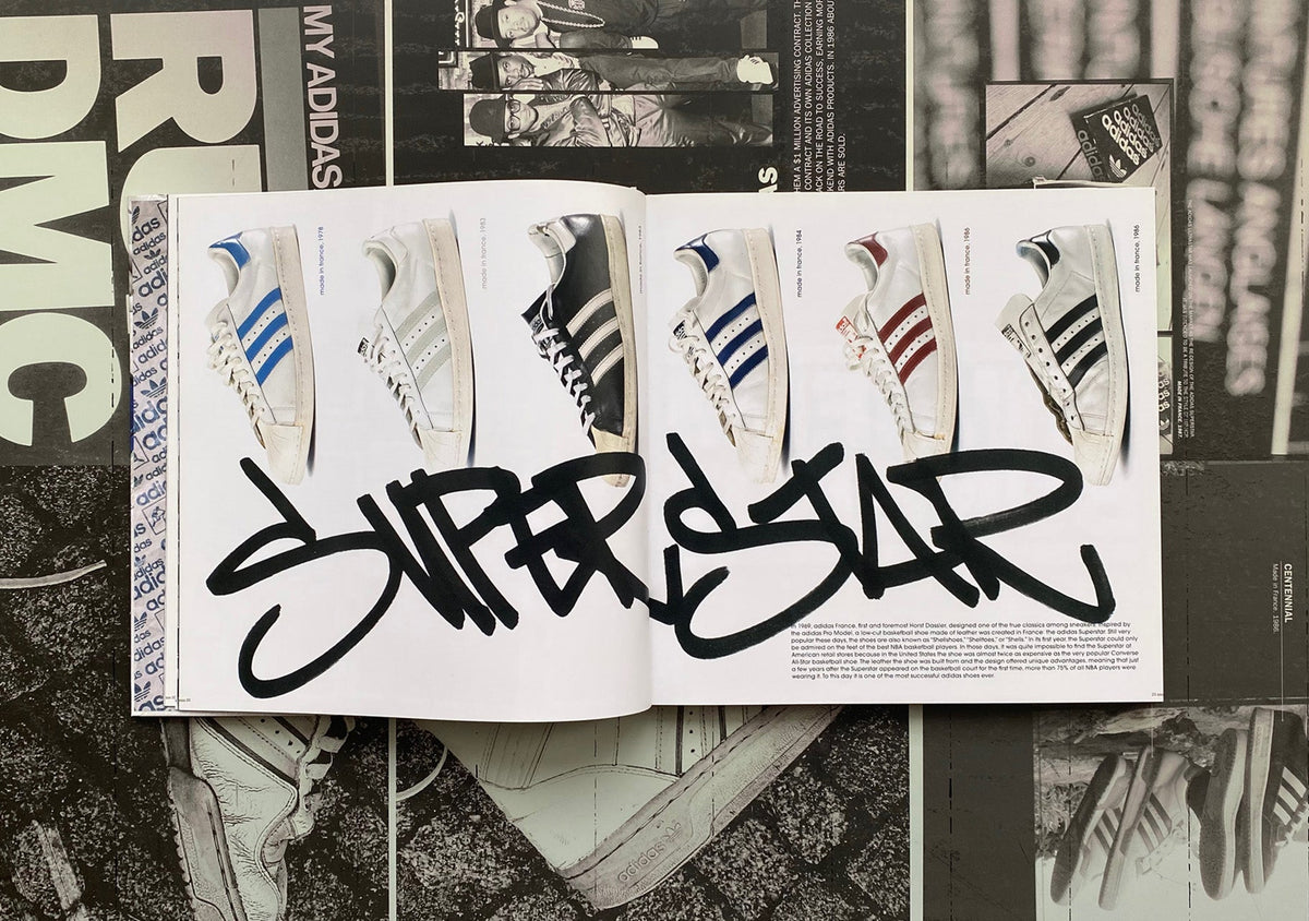 Aufgeschlagenes Buch zeigt sechs Sneaker und den Graffiti-Schriftzug SUPERSTAR auf weißem Hintergrund.