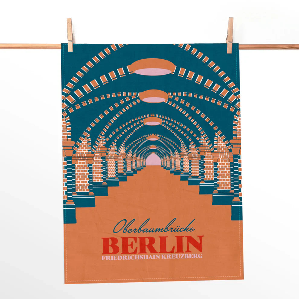 Geschirrtuch mit grafischem Motiv der Oberbaumbrücke in Türkis und Orange mit Berliner Schriftzug.