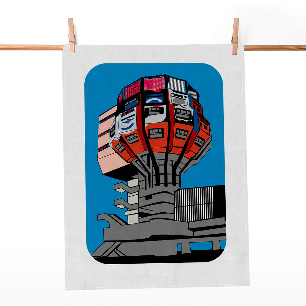 Weißes Geschirrtuch mit grafischem Motiv des Berliner Fernsehturms vor blauem Hintergrund an einer Holzleiste.