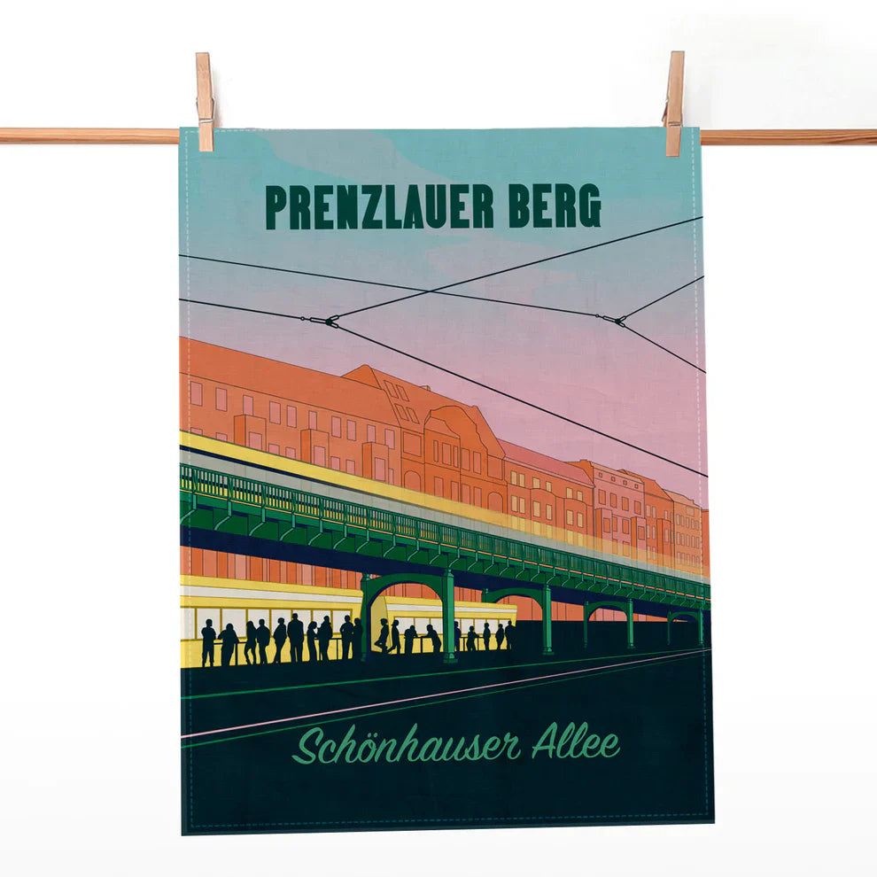 Geschirrtuch mit Illustration der Hochbahn Schönhauser Allee im Bezirk Prenzlauer Berg an einer Holzleiste aufgehängt.