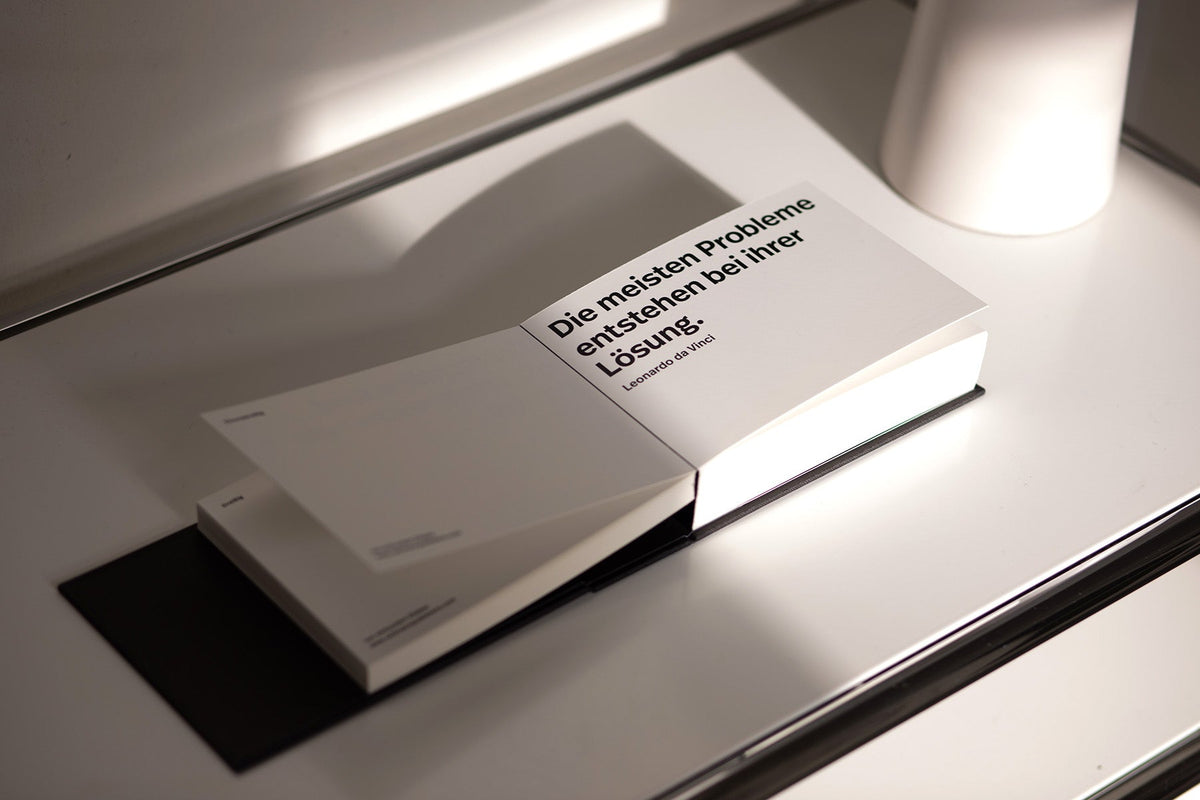 Aufgeschlagenes Buch mit weißem Cover und dem Zitat Die meisten Probleme entstehen bei Ihrer Lösung.