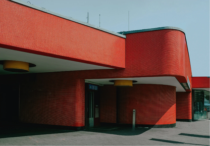 Rotes Gebäude mit geschwungener Außenwand und Außentreppe