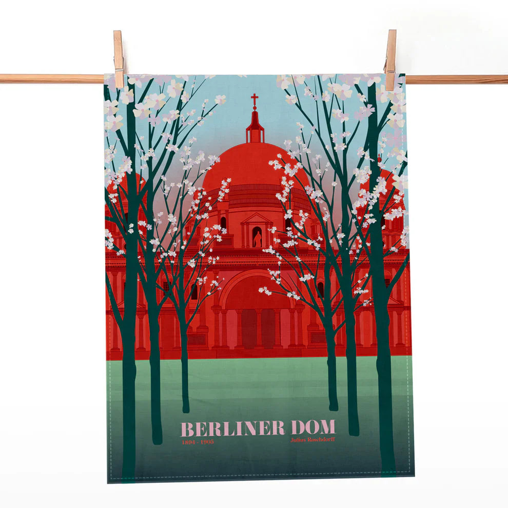 Geschirrtuch mit roter Illustration des Berliner Doms und blühenden Bäumen vor blauem Himmel.
