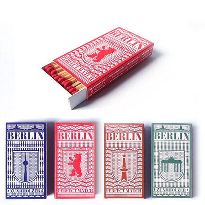 Rote und blaue Streichholzpackung mit "BERLIN PERFECT MATCH" und SWERT-Logo. Drei identische Boxen mit "ZUNDHOLZER".
