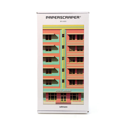 Weiße Verpackung des Paperscraper Miami mit farbenfroher Hotel-Fassade in Rosa und Türkis.